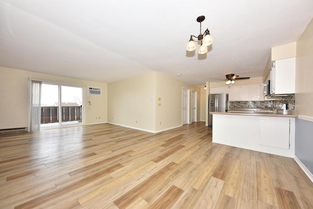 kitchen with stainless steel appliances, white cabinets, open floor plan, an AC wall unit, and backsplash