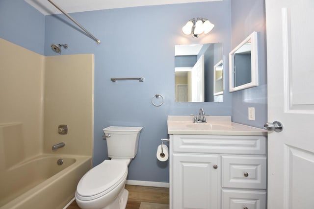 bathroom with bathing tub / shower combination, toilet, vanity, wood finished floors, and baseboards