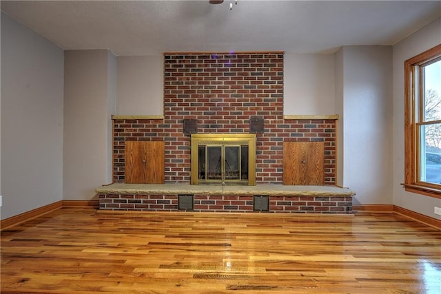 unfurnished living room featuring light wood-type flooring, visible vents, a fireplace, and baseboards