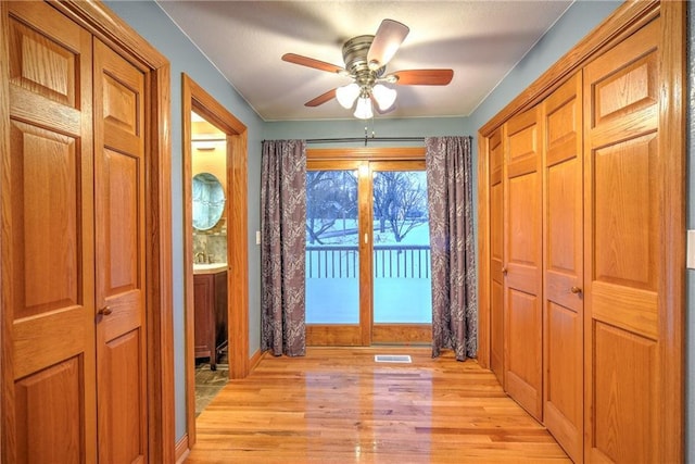 entryway with visible vents, ceiling fan, a sink, and light wood finished floors