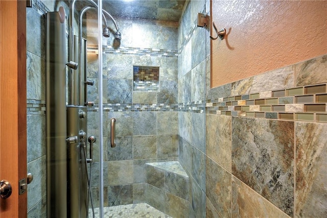 bathroom with a textured wall and a shower stall