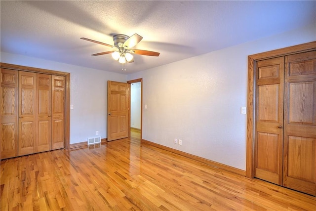 unfurnished bedroom with light wood-type flooring, baseboards, visible vents, and a textured ceiling