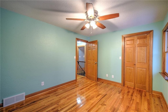 unfurnished bedroom featuring light wood-type flooring, a closet, visible vents, and baseboards