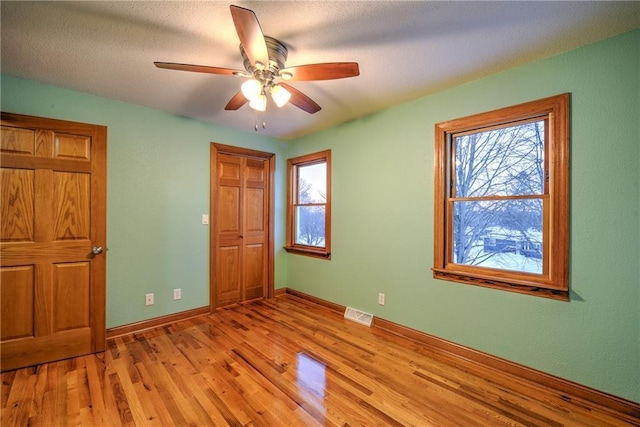 unfurnished bedroom featuring a closet, visible vents, a ceiling fan, light wood-type flooring, and baseboards