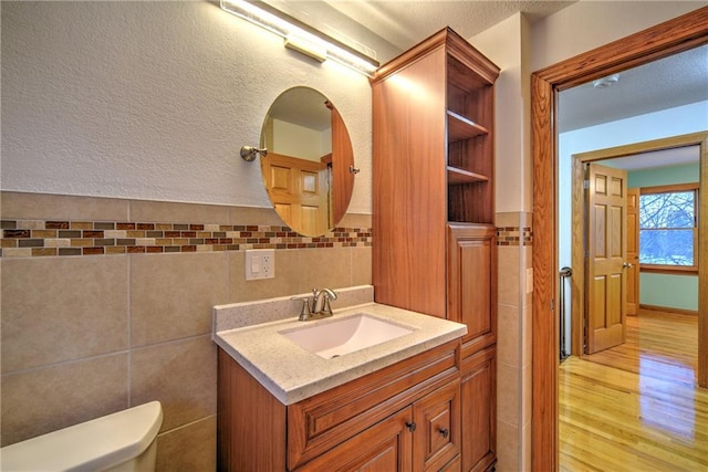 bathroom featuring vanity, tile walls, toilet, and wood finished floors