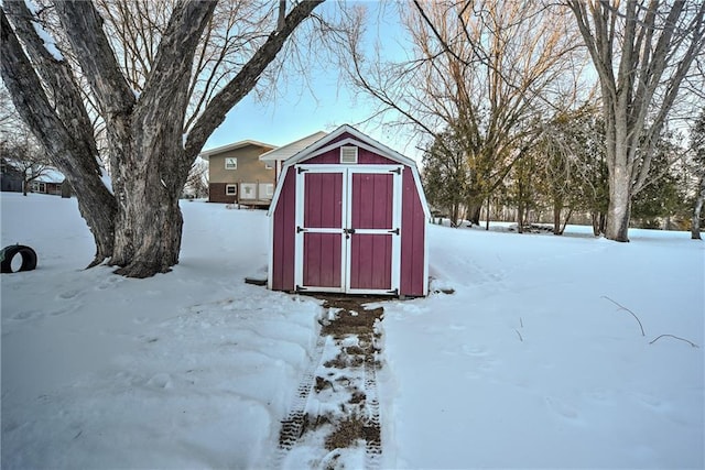 snow covered structure with an outbuilding and a storage unit