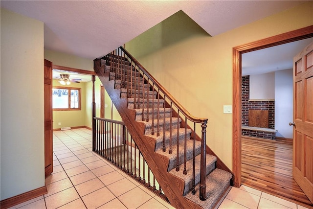 stairway with a fireplace, tile patterned flooring, and baseboards