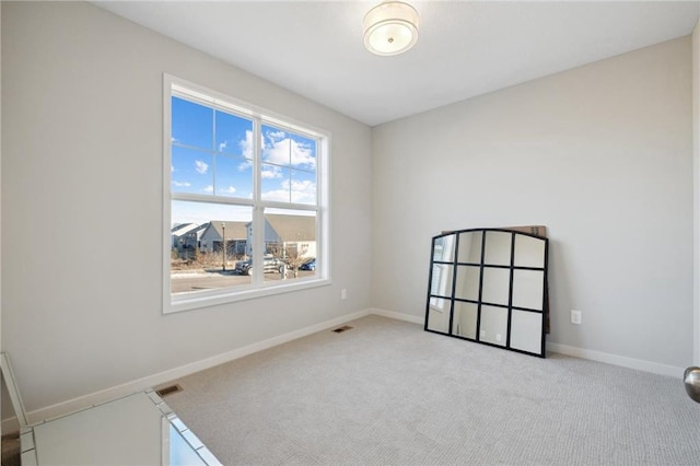 spare room featuring visible vents, baseboards, and light colored carpet