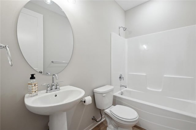 bathroom with shower / washtub combination, a sink, toilet, and baseboards