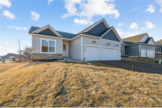 view of front facade with aphalt driveway, board and batten siding, a garage, stone siding, and a front lawn