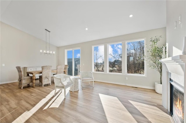 interior space featuring light wood-type flooring, a wealth of natural light, lofted ceiling, and a lit fireplace