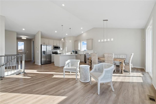 living area with lofted ceiling, light wood-style flooring, recessed lighting, visible vents, and an inviting chandelier