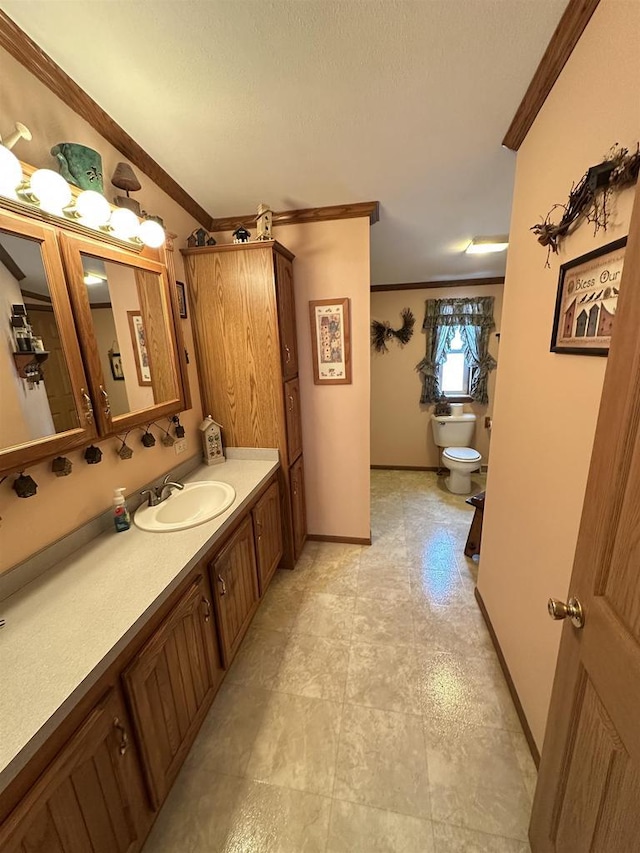 bathroom with baseboards, vanity, toilet, and crown molding