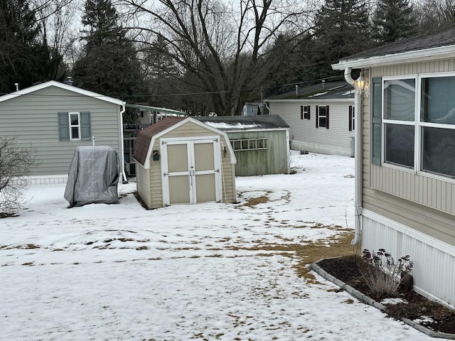 snow covered structure featuring a shed and an outbuilding