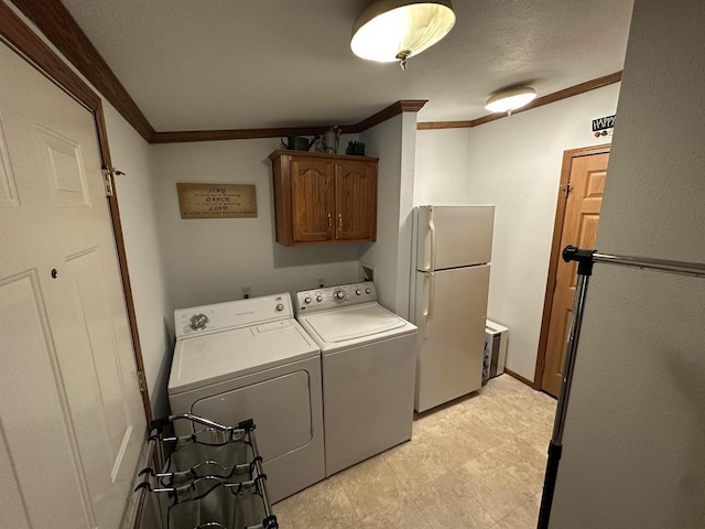 clothes washing area featuring ornamental molding, washer and dryer, and cabinet space