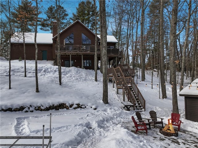 snow covered house featuring stairway, log veneer siding, a fire pit, and a deck