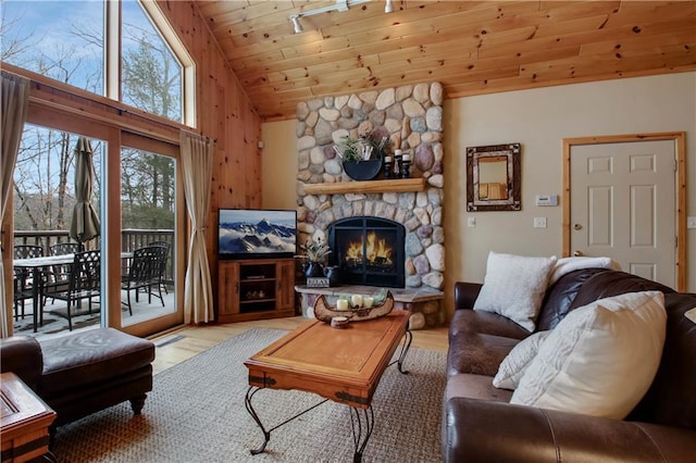 living area with lofted ceiling, wooden ceiling, light wood-type flooring, and a stone fireplace