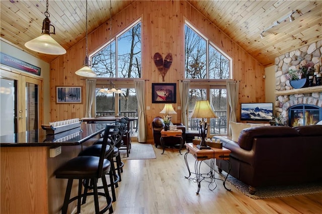 living area featuring wood ceiling, wooden walls, light wood-style flooring, and a fireplace