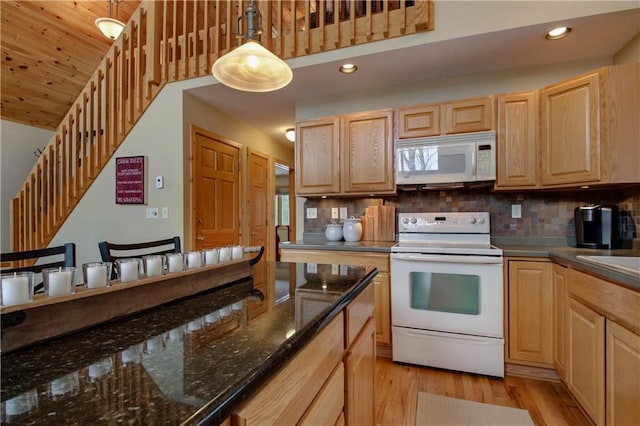 kitchen featuring pendant lighting, dark stone counters, white appliances, and light brown cabinetry