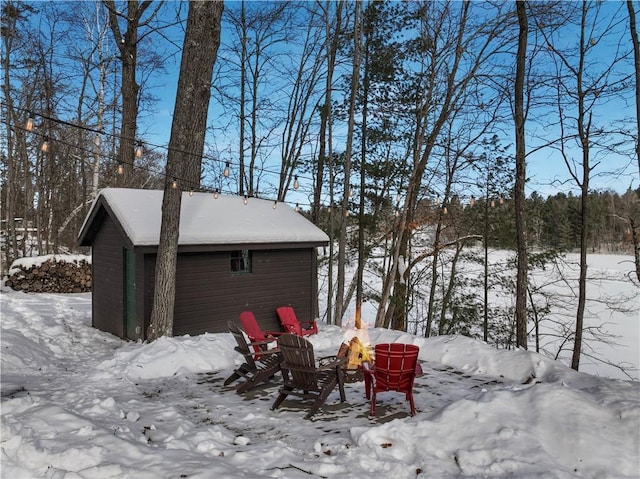 yard covered in snow with a fire pit and an outdoor structure