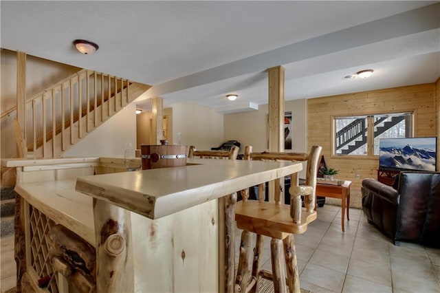 kitchen with a breakfast bar, open floor plan, light tile patterned flooring, and wooden walls