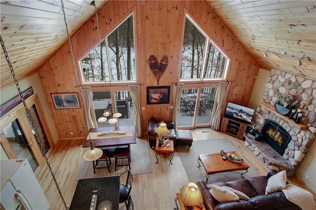 living area with a fireplace, wooden walls, wood finished floors, high vaulted ceiling, and wooden ceiling