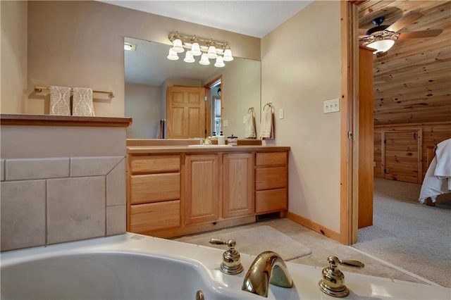 full bathroom with baseboards, a washtub, vanity, and a ceiling fan