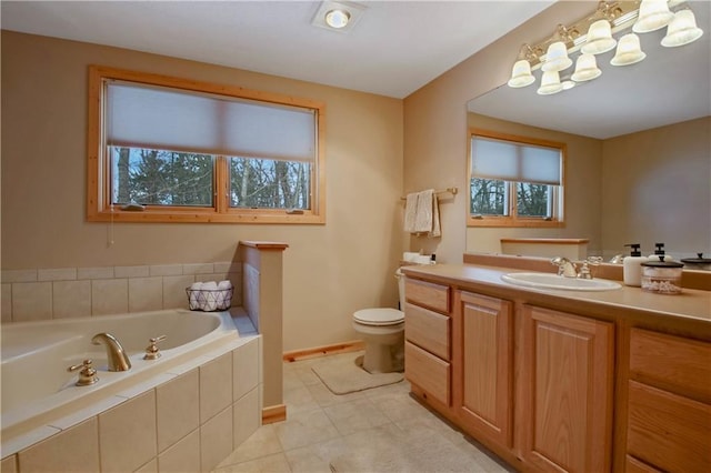 bathroom with a garden tub, toilet, vanity, baseboards, and tile patterned floors