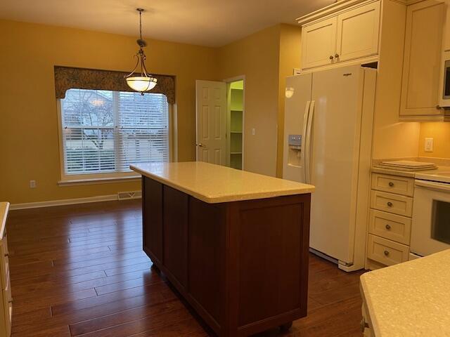 kitchen with white appliances, a center island, light countertops, and decorative light fixtures