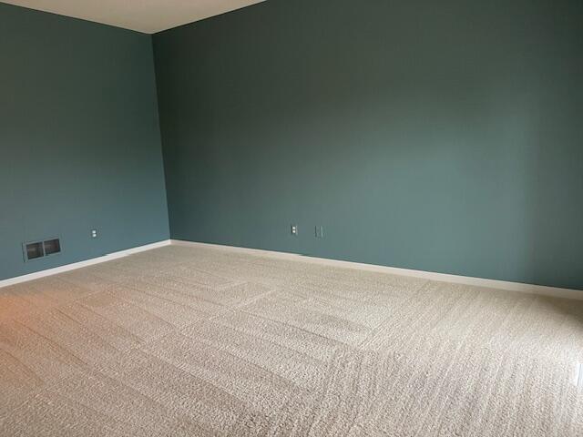 unfurnished room featuring carpet, visible vents, and baseboards