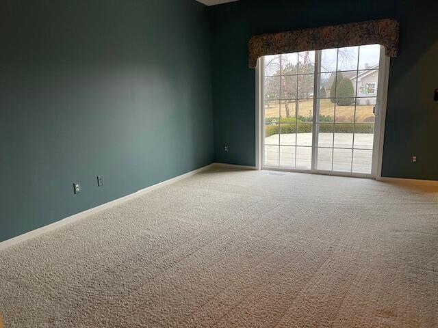 spare room featuring carpet floors and baseboards