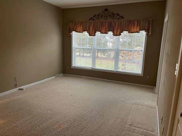 empty room featuring light carpet and baseboards