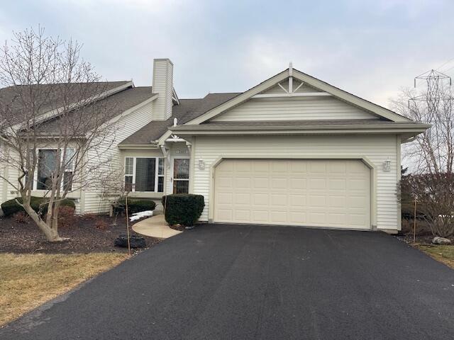 view of front of property with driveway, a garage, and a chimney