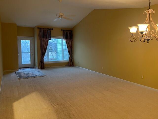 interior space featuring lofted ceiling, light colored carpet, and ceiling fan with notable chandelier