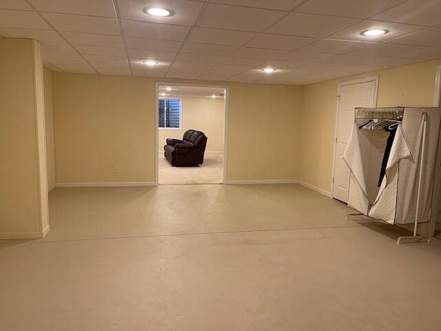 finished basement featuring a paneled ceiling, baseboards, and recessed lighting