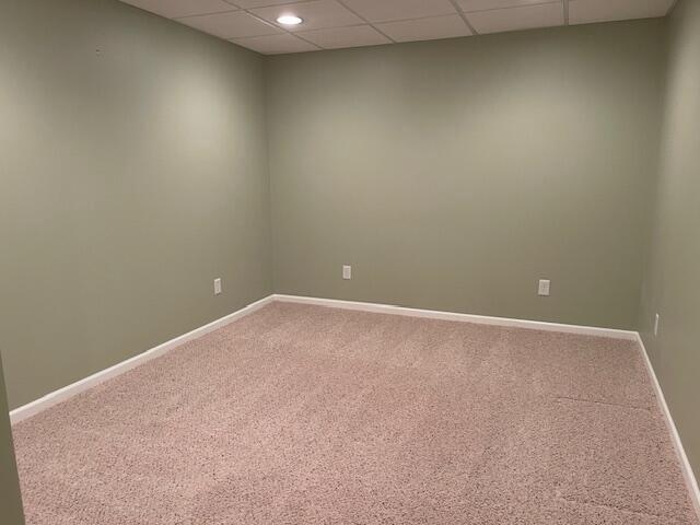 unfurnished room with a paneled ceiling, carpet, and baseboards