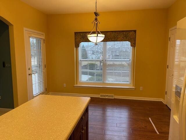 unfurnished dining area featuring visible vents, baseboards, and dark wood-type flooring