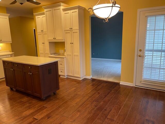 kitchen with baseboards, dark wood finished floors, ceiling fan, hanging light fixtures, and light countertops