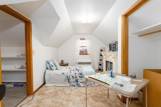 bedroom with lofted ceiling, radiator, a fireplace, and baseboards