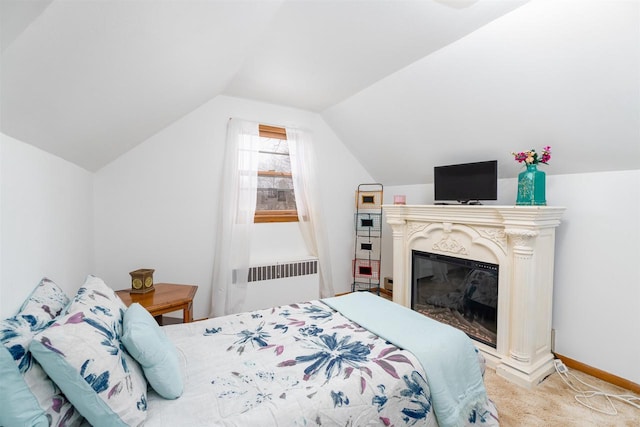 bedroom with lofted ceiling, carpet flooring, baseboards, radiator, and a glass covered fireplace