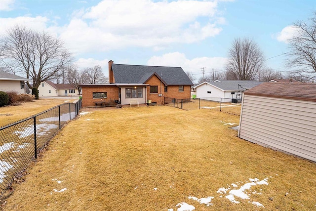 rear view of property featuring a fenced backyard, a chimney, a lawn, and brick siding