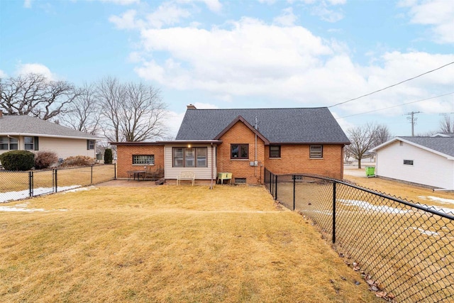 view of front of home featuring a fenced backyard, a front yard, roof with shingles, and brick siding