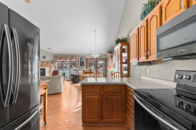 kitchen with brown cabinets, light countertops, electric range, freestanding refrigerator, and a peninsula