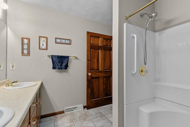 bathroom with double vanity, a shower, a sink, and visible vents