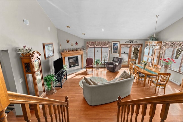 living room featuring a chandelier, a high end fireplace, a healthy amount of sunlight, and light wood-style flooring