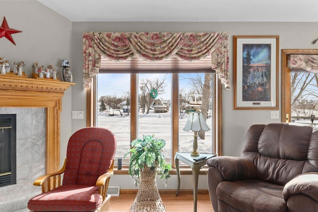 living area featuring a healthy amount of sunlight, a fireplace, visible vents, and wood finished floors