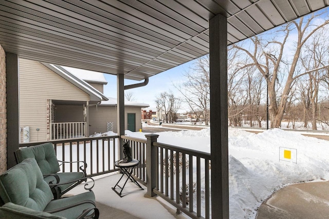 snow covered back of property featuring a porch