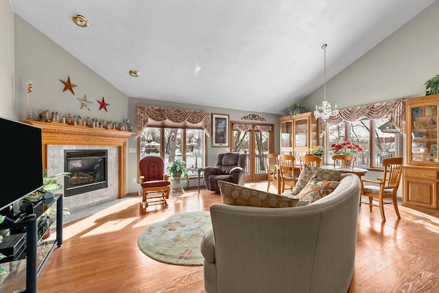 living area with high vaulted ceiling, light wood-style flooring, a fireplace, and a chandelier