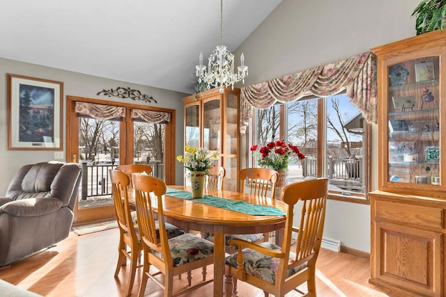 dining area featuring french doors, lofted ceiling, a chandelier, light wood-type flooring, and baseboards