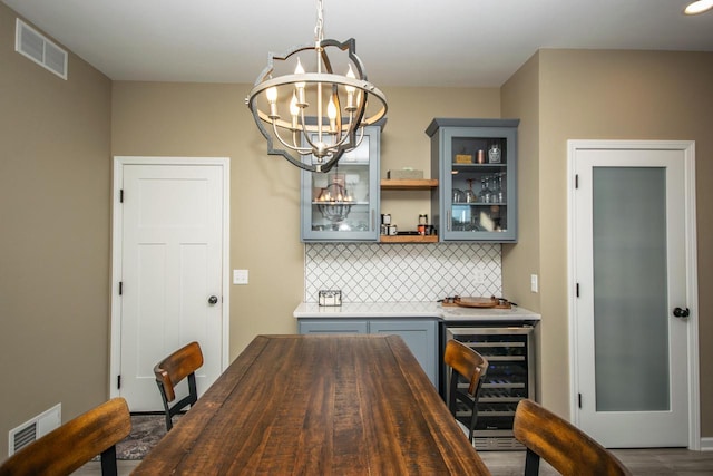 dining space featuring a dry bar, wine cooler, visible vents, and a chandelier